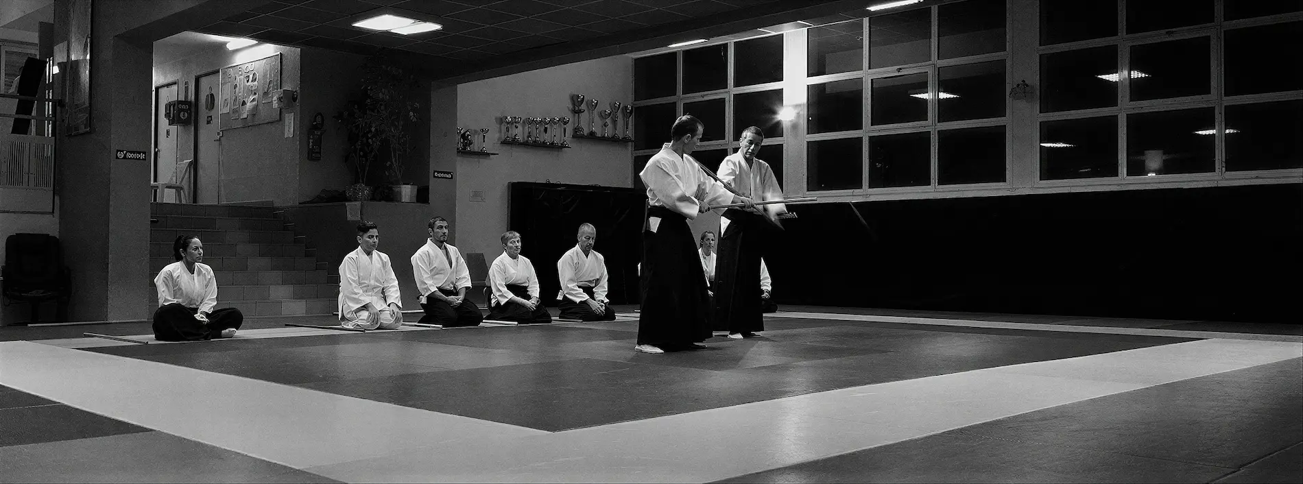 Pratiquants d'aïkido en hakama sur le tatami du dojo, en noir et blanc